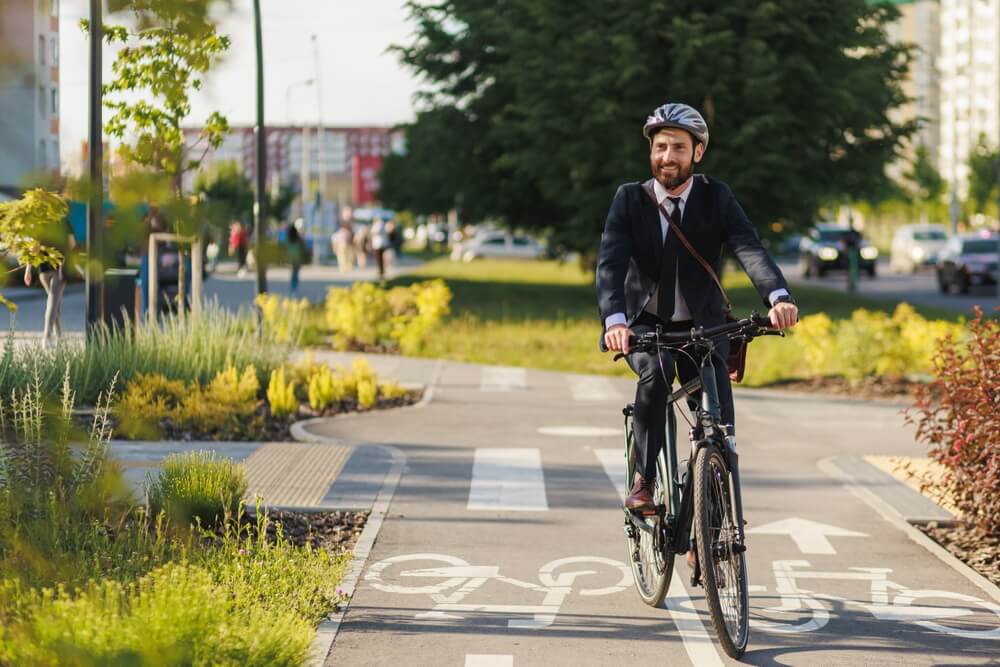 Happy office clerk in smart casual smiling, while riding after work in downtown.