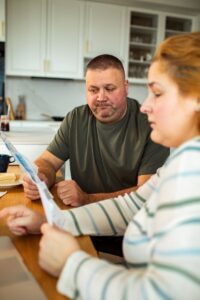 Worried couple reviewing a stack of bills together at their kitchen table